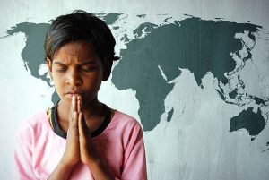 Child praying in front of a map of the world